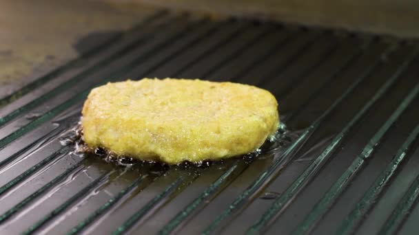 Closeup of oily bubbles under chicken burger while grilling on big hot surface — Stock Video