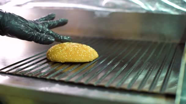 Close-up chef hand zet hamburgerbroodjes op grill en past olie met siliconen borstel — Stockvideo