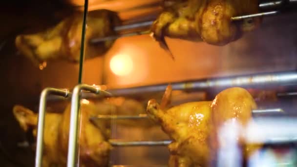 Closeup of whole chicken rotate slowly in rotisserie grill — Stock Video