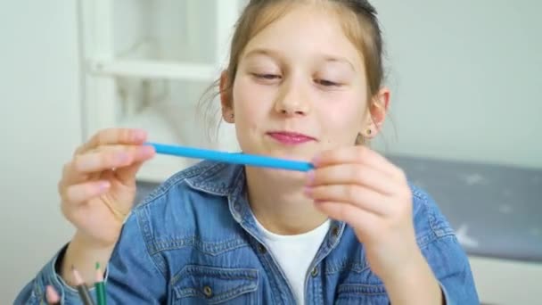 Rolig tjej tittar på kameran och göra ansikten med färgade pennor som mustasch — Stockvideo