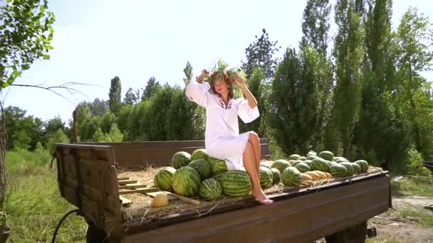 Meisje in traditionele Oekraïense jurk zittend in trailer met watermeloenen buiten — Stockvideo