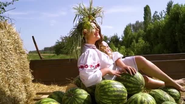 Dziewczyna w tradycyjnym słowiańskim stroju siedzącego w przyczepie z arbuz na zewnątrz — Wideo stockowe