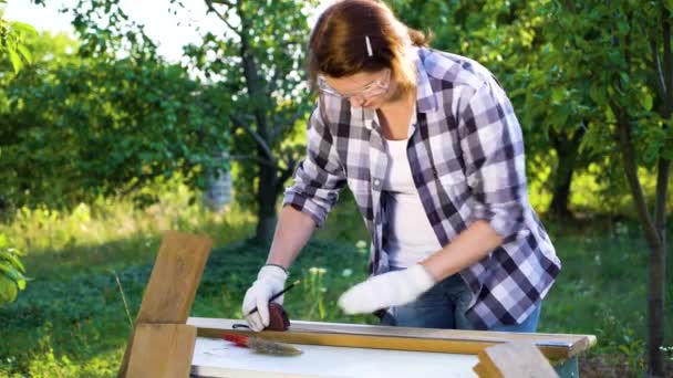 Falegname femminile misura assi di legno con nastro di misurazione in giardino soleggiato — Video Stock