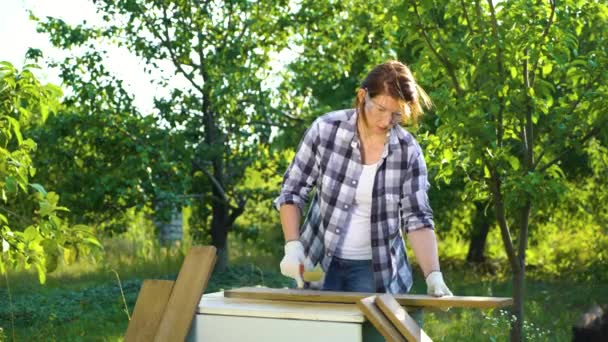 Artesanía mujer lijar tablón de madera vieja manualmente con cepillo de metal en jardín soleado — Vídeos de Stock