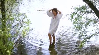 Nehirde duran ve saçlarına dokunan etnik elbiseli kız