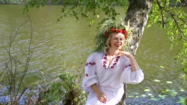 Pretty woman in slavic traditional costume lying on trunk of birch tree — Stock Video