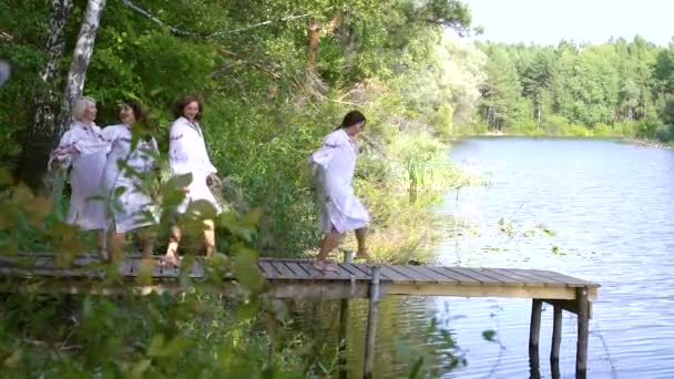 Pretty women in ethnic dresses and circlets running on pontoon bridge — Stock Video