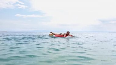 Denizde şişme yatak üzerinde yüzen neşeli kızlar