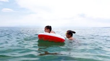 Yaz tatilinin tadını çıkaran kızlar mavi denizde yüzmek