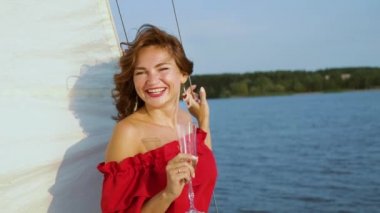 Güzel kadın kameraya gülümseyen ve yelkenli teknede rahatlatıcı