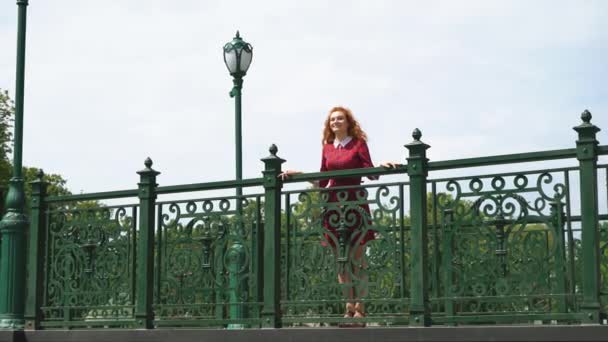Glad rödhåriga tjejen står på smidda Bridge — Stockvideo