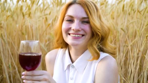 Felice ragazza dai capelli rossi bere vino al picnic nel campo di grano — Video Stock