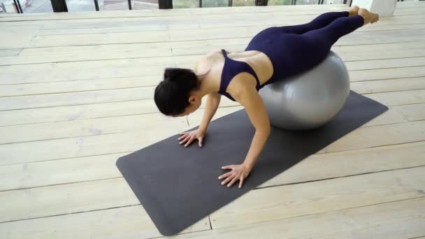 Entrenamiento de mujer joven y deportiva con pelota de fitness — Vídeo de stock