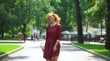 Kendine güvenen kırmızı saçlı kız şemsiye ile parkta yürüyüş