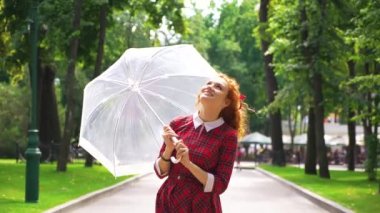 Güneşli parkta şemsiye ile oynayan pozitif kız