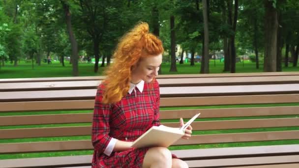 Schattig rood haired meisje lezen grappig boek in Park — Stockvideo