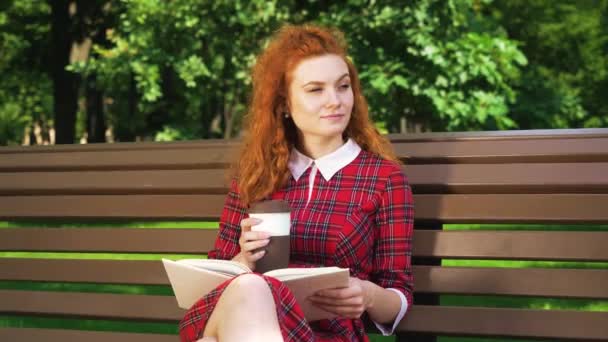 Amable lector de pelo rojo relajándose en el parque — Vídeos de Stock