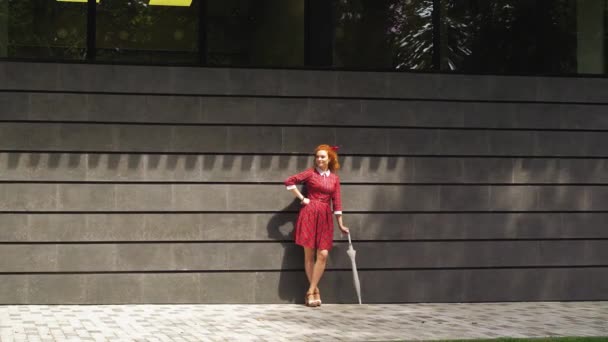 Cheerful red haired girl standing with umbrella outside — Stock Video