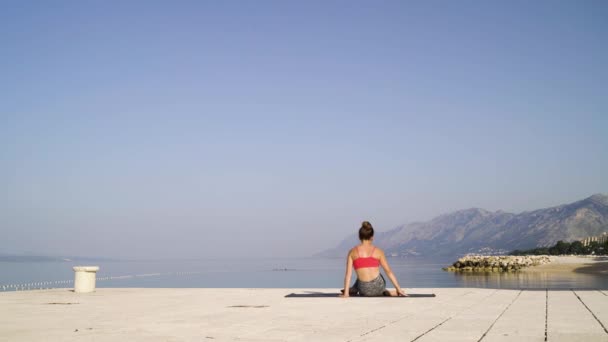 Крепкая женщина медитирует в позе йоги у моря — стоковое видео