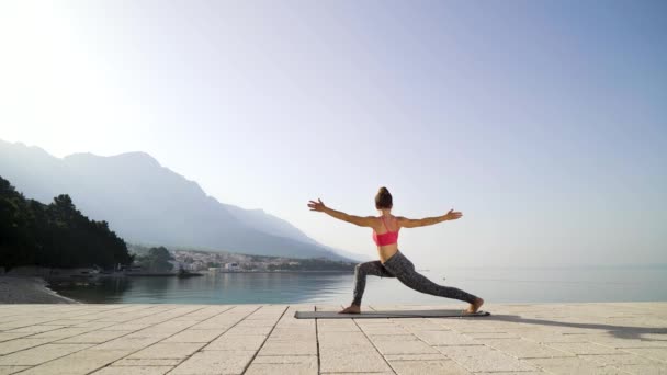 Sportig passform kvinna tränar yoga vid havet på morgonen — Stockvideo