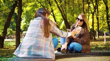 Sonbahar parkında akıllı telefon uygulamaları kullanan cana yakın kızlar.