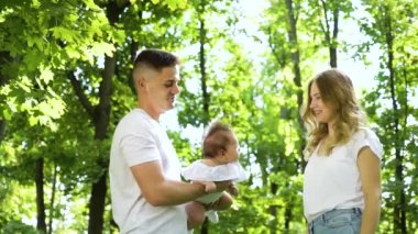 Sevimli bebeği olan sevimli bir aile yaz bahçesinde eğleniyor.