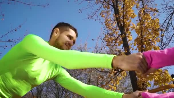 Gelukkige paar atleten hand in hand en het doen van pair oefeningen buiten — Stockvideo