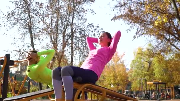 Pareja de atletas haciendo ejercicios abdominales en el campo de deportes en un día soleado — Vídeo de stock