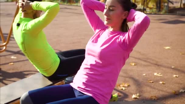 Ajuste pareja ejercicio de ejercicios abdominales en el campo de deportes por la mañana — Vídeo de stock