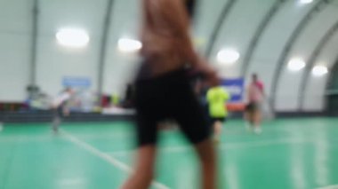 Raketli bulanık çocuklar badminton kortunda toplanıyor.