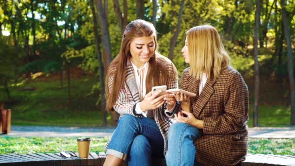 Succesvolle fashion bloggers met smartphones in zonnig park — Stockvideo