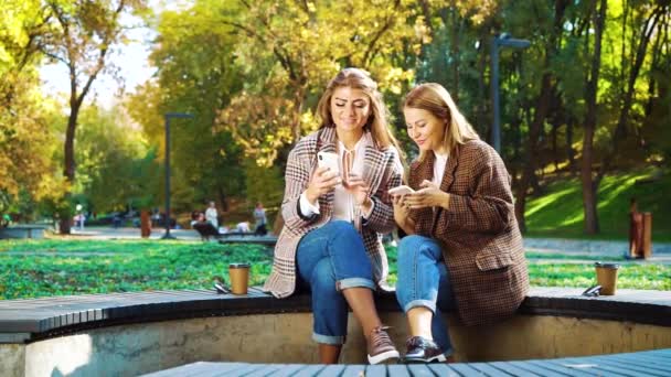 Amigos alegres usando smartphones fora no parque público — Vídeo de Stock
