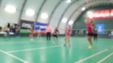 Sahada badminton raketleriyle pratik yapan bulanık çocuklar.