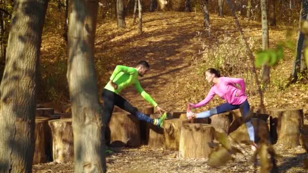 Glada par tränar tillsammans på stubbar i höstskogen — Stockvideo