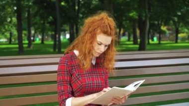 Mutsuz kızıl saçlı kız parkta gerilim romanı okuyor