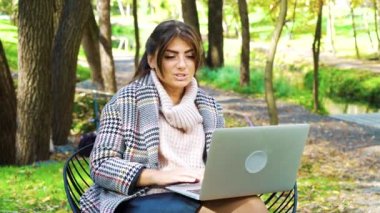 Webinar 'ı parkta otururken göstermek için dizüstü bilgisayar kullanan başarılı konuşmacı