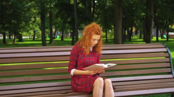 Красива дівчина читає сумну книгу в зеленому парку — стокове відео