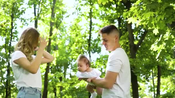 Glad ung familj med liten flicka tillbringar sommaren i trädgården — Stockvideo
