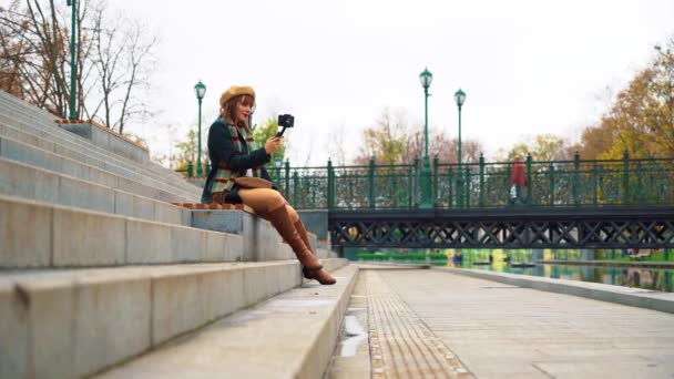 Vlogger de moda con smartphone y steadicam para grabar vídeo en el parque — Vídeo de stock