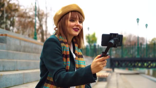 Молодой блоггер потоковое из общественного парка с помощью смартфона и стабикам — стоковое видео