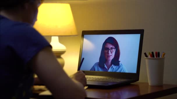 Νεαρή γυναίκα που παρακολουθεί μαθήματα online στο φορητό υπολογιστή στο σπίτι το βράδυ — Αρχείο Βίντεο