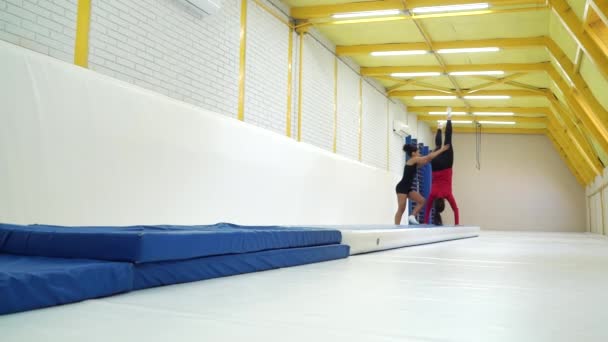 Filles sportives pratiquant le handstand et le saut périlleux sur des nattes dans la salle de gym — Video