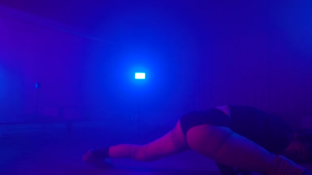 Sexig tjej sitter i split och dansande twerk i mörk studio — Stockvideo