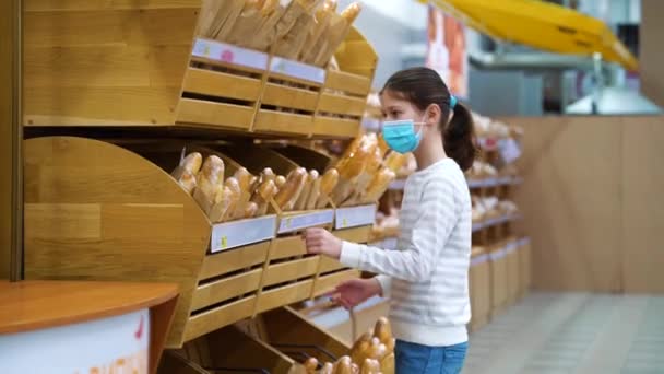 Klein meisje koopt verse stokbrood in de supermarkt tijdens de pandemie — Stockvideo