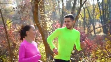 Sabahları güz parkında koşan neşeli iki koşucu.