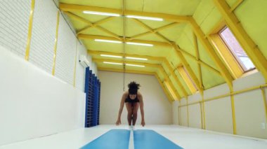 Afrikalı Amerikalı kız antrenman sırasında bir dizi takla atıyor.