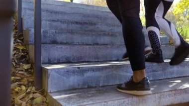 Spor ayakkabılı bir kadın parktaki beton merdivenlerde yürüyor.