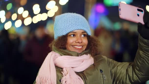 Happy black girl blogger live streaming from holiday market at night — Stock Video