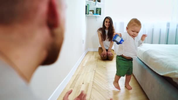 Criança bonito fazendo primeiros passos de mãe para pai em casa — Vídeo de Stock