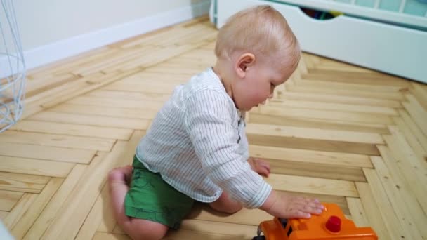 Härligt leksakspojke som leker med leksaksbilen på golvet — Stockvideo